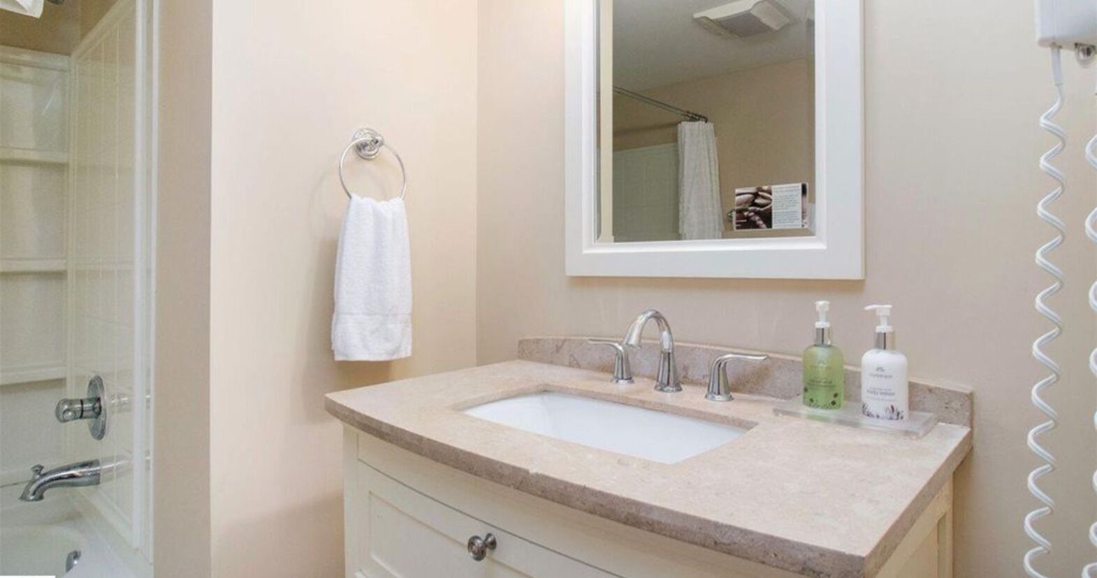 A bathroom with a double sink, a mirror, a towel rack, and a shower.