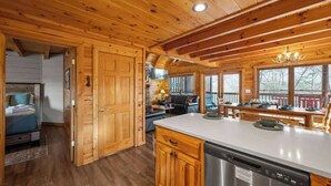 A wooden cabin interior with a kitchen, dining area, and a bedroom. - Pigeon Forge|Pool·Hot Tub|Game&Theater Rm·Pets·EV (Pigeon Forge)