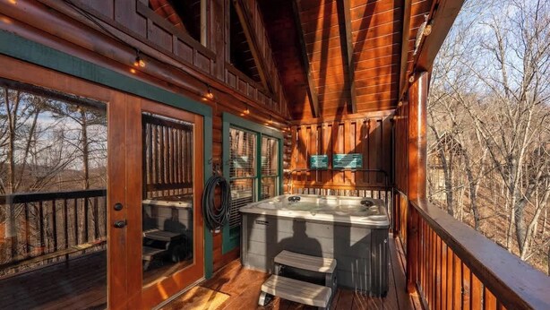 A wooden deck with a hot tub, a bench, and a view of trees. - Pigeon Forge|Pool·Hot Tub|Game&Theater Rm·Pets·EV (Pigeon Forge)