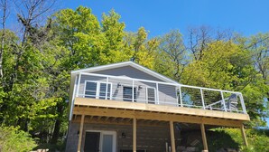 Une cabane à deux étages dotée d’un balcon, entourée d’arbres.