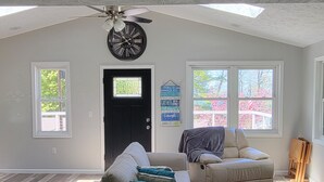 Un salon spacieux avec un plafond haut, un ventilateur de plafond et de grandes fenêtres.