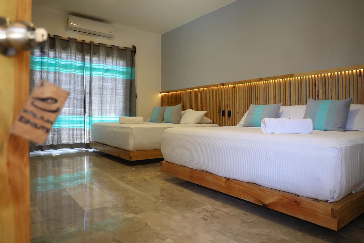 A hotel room with two beds, a wooden headboard, and a curtain with a striped pattern.
