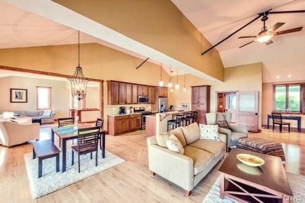 Amplia sala de estar con una mesa de comedor, sofá y cocina al fondo.