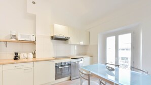 Eine moderne Küche mit weißen Schränken, einer Holz Arbeitsplatte und einem Glastisch für Essbereich.