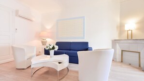 Ein modernes Wohnzimmer mit einem blauen Sofa, weißen Sesseln und einem weißen Couchtisch.