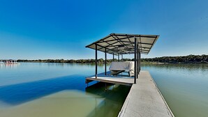 Um cais coberto com uma única cadeira de descanso e uma pequena mesa, com vista para águas calmas.