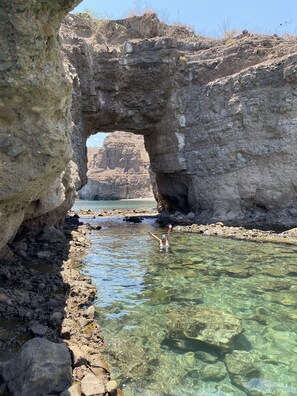 A natural rock formation with a clear water channel and a person swimming.