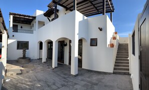 A white building with a courtyard, a fountain, and a staircase leading to an upper level.