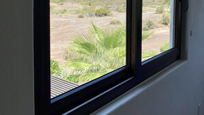 A window with a view of a desert landscape and the ocean. - Casa Canto Del Mar (Fraccionamiento Nopolo, Loreto baja cali)