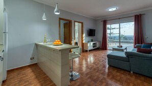 En moderne stue med sofa, et spiseområde med bar og en balkon med udsigt.