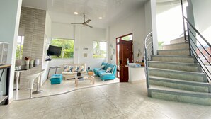 A spacious living area with a high ceiling, a staircase, and a kitchen area with a TV. - 🏅 Mediterranean Beach Style Villa with Private Pool & Jacuzzi (Tocaima)
