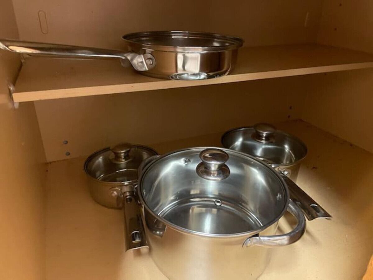 A kitchen with stainless steel cookware on shelves.