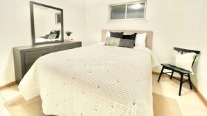 A bedroom with a bed, a bedside table, a chair, a dresser, a mirror, and a window. - Safe NOLA-steps to Ochsner hospital! (Jefferson)