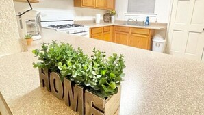 A kitchen with wooden cabinets, a granite countertop, and a plant arrangement spelling "HOME". - Safe NOLA-steps to Ochsner hospital! (Jefferson)