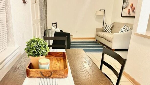 A dining area with a wooden table, chairs, a tray with a plant and a jar, and a sofa in the background. - Safe NOLA-steps to Ochsner hospital! (Jefferson)
