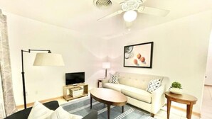 A living room with a sofa, coffee table, floor lamp, TV, and a ceiling fan. - Safe NOLA-steps to Ochsner hospital! (Jefferson)