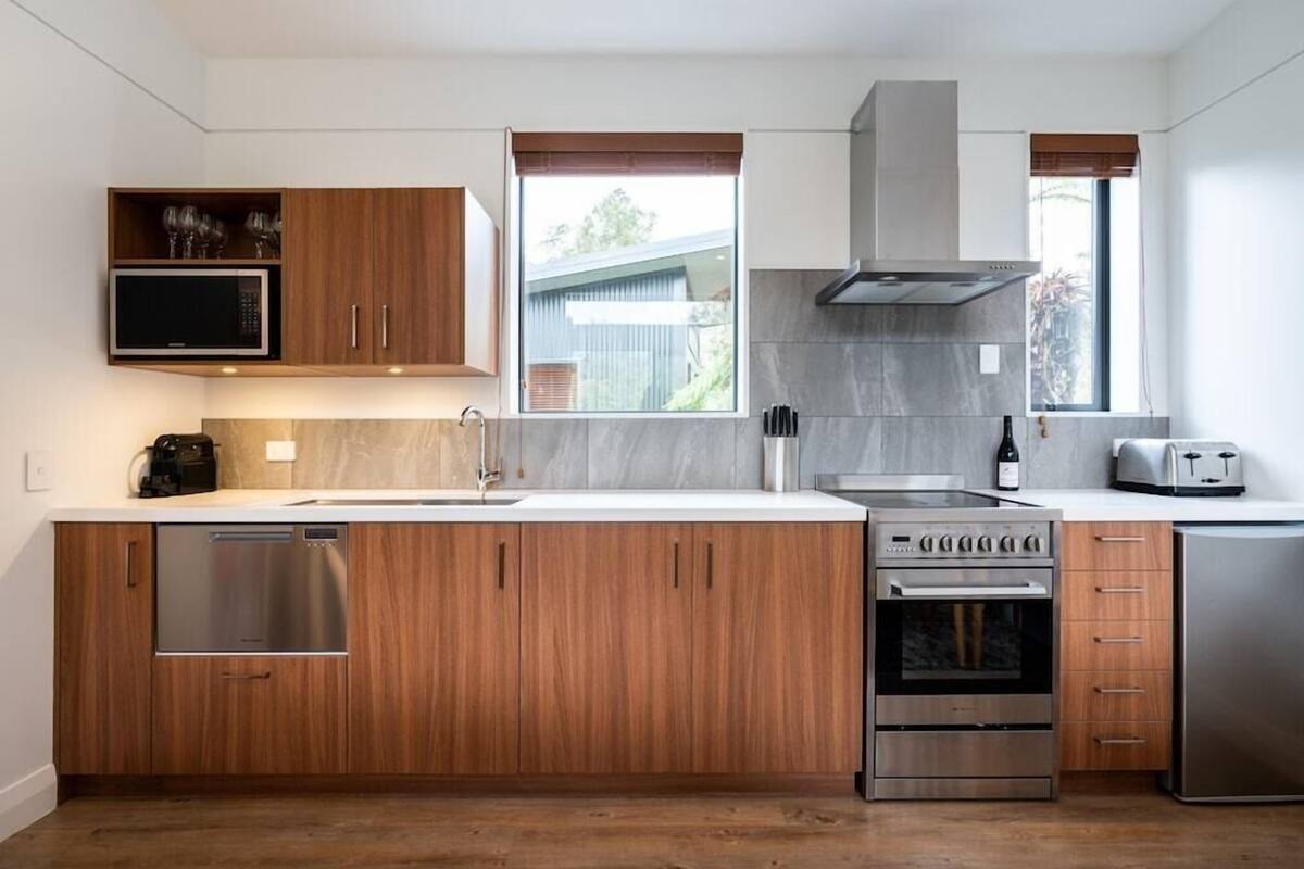 A modern kitchen with wooden cabinets, stainless steel appliances, a built-in microwave, and a window with a view.