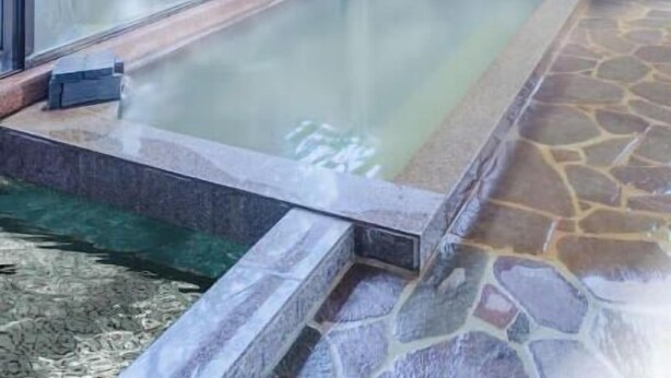 A hot spring bath area with stone steps leading into the water, a tiled floor around the bath, and a glass door.
