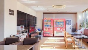 A modern lounge area with seating, vending machines, and a television.