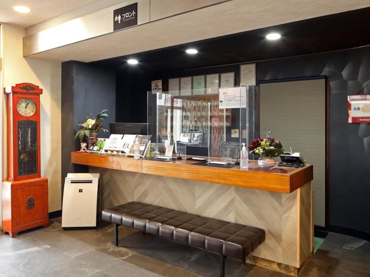 A reception desk with a wooden counter, a bench, a clock, and a small air purifier.
