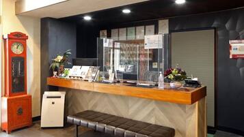 A reception desk with a wooden counter, a bench, a clock, and a small air purifier.