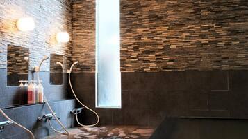 A modern bathroom with a stone wall, a large window, and a bathtub.