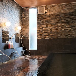 A modern bathroom with a stone wall, a large window, and a bathtub. - Aso Uchinomaki Onsen Gogaku Hotel (Aso)