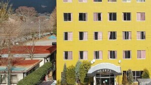 A yellow building with a sign above the entrance, a clear sky, and mountains in the background.