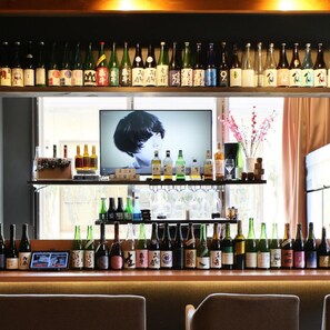 A bar area with shelves of bottles and a television screen. - Aso Uchinomaki Onsen Gogaku Hotel (Aso)
