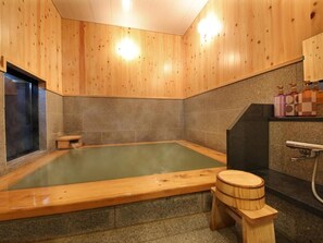A wooden-finished spa room with a large soaking tub, a wooden stool, and a small bench. - Aso Uchinomaki Onsen Gogaku Hotel (Aso)