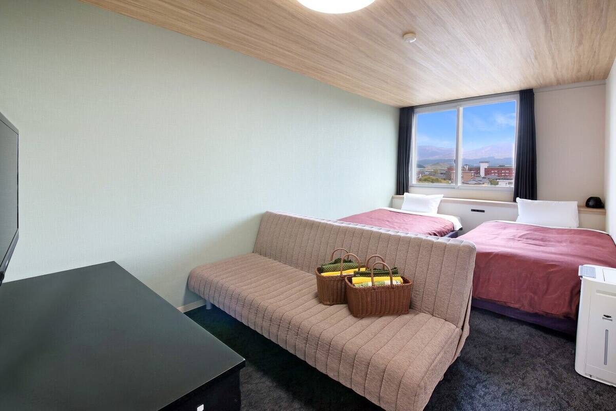 Habitación de hotel con cama, sofá, escritorio y televisor.
