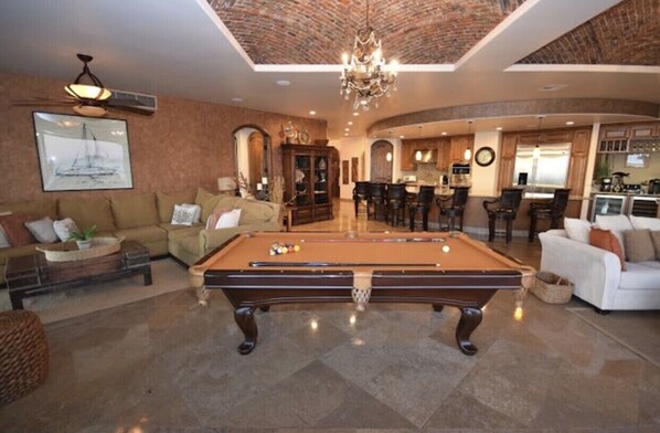 A spacious living area with a pool table, a sofa, and a dining area.
