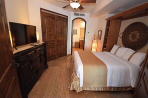 A bedroom with a large bed, wooden wardrobe, and a television on a dresser.