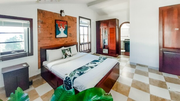 A bedroom with a bed, a wooden headboard, a window, a wardrobe, and a checkered floor. - Sun Villa (Nam Nha Trang)