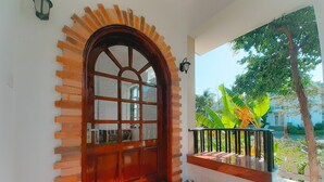 A wooden door with glass panels, a brick archway, and a balcony with a railing. - Sun Villa (Nam Nha Trang)
