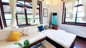 A room with a sofa, a bed, a small table, and a window with curtains. - Sun Villa (Nam Nha Trang)
