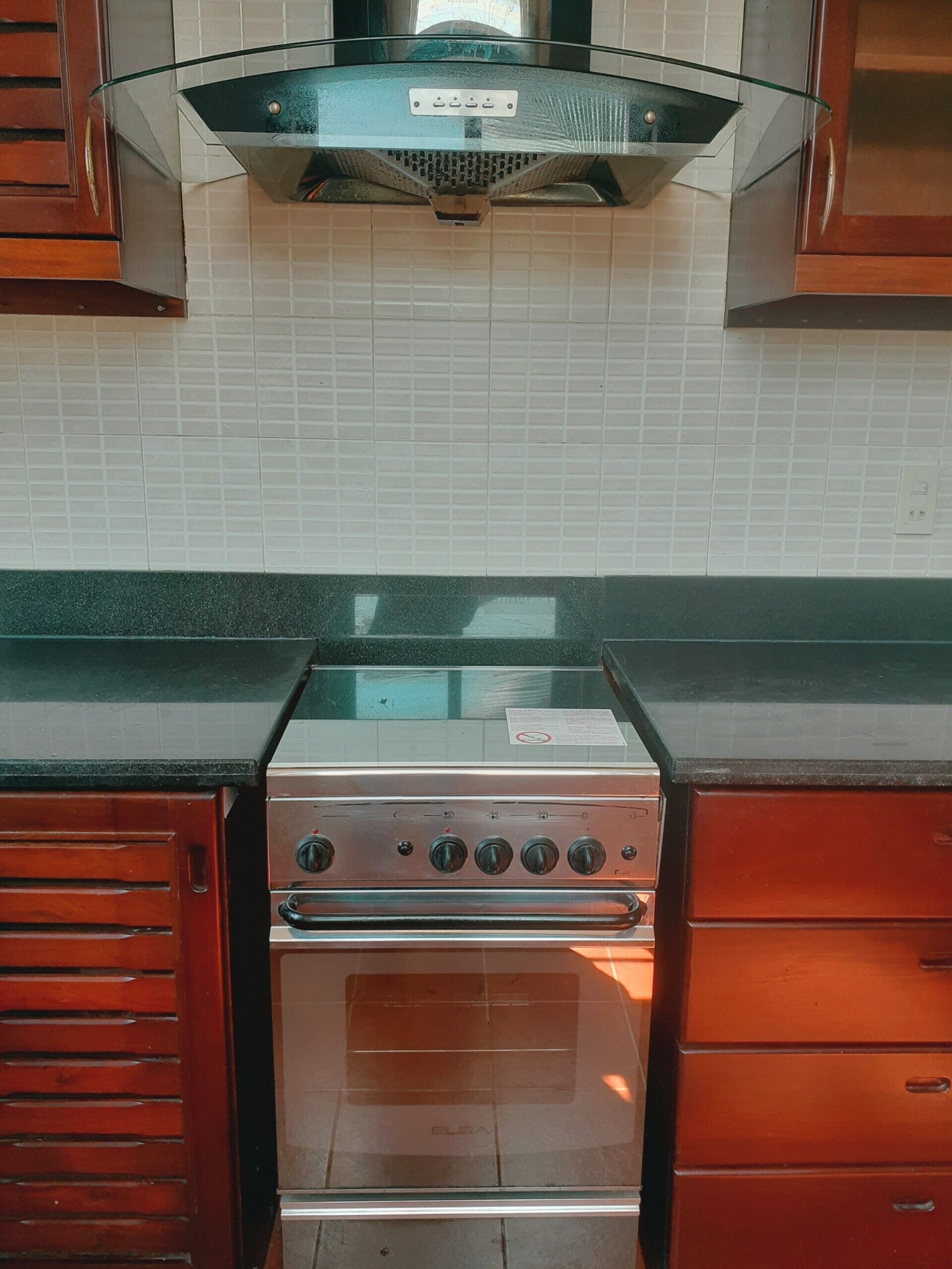 A kitchen with a stainless steel stove, wooden cabinets, and a tiled backsplash.