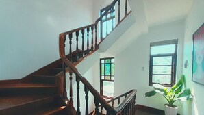 A wooden staircase with a handrail, leading to an upper floor. There are windows on the walls, and a potted plant is visible on the lower landing. - Sun Villa (Nam Nha Trang)