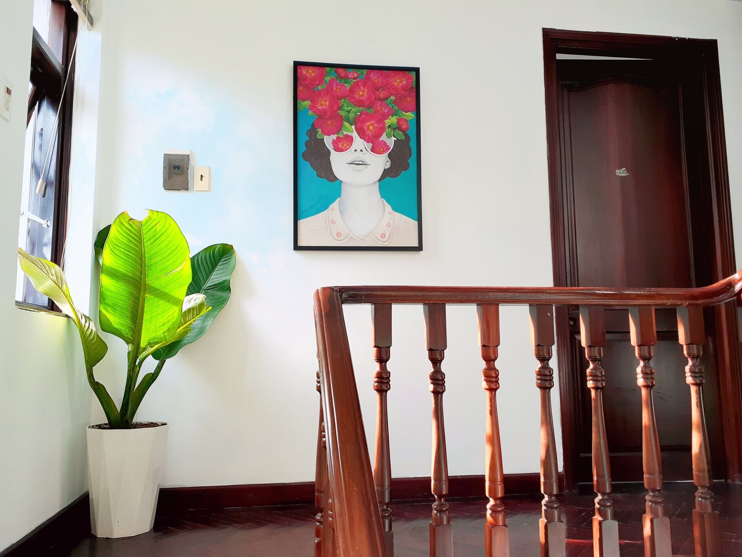 A staircase with wooden balusters, a potted plant, and a framed artwork on the wall.