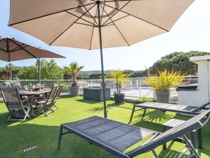 Une terrasse extérieure avec une table et des chaises, un grand parasol et des plantes en pot.