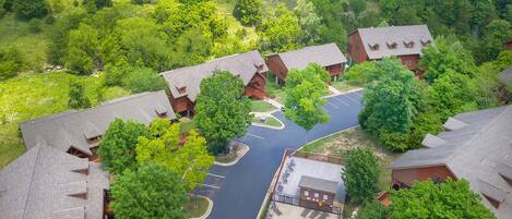An aerial view of a resort with multiple cabins, a swimming pool, and surrounding greenery.