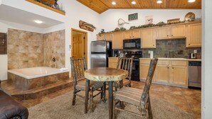 A kitchen with wooden cabinets, a refrigerator, a microwave, and a dishwasher. - Romantic Hideaway Walk-in Cabin for Two - Fireplace & Whirlpool Tub (Branson)
