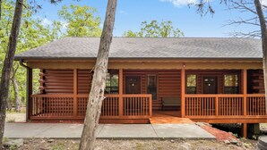A log cabin with a porch, wooden railings, and a bench. - Romantic Hideaway Walk-in Cabin for Two - Fireplace & Whirlpool Tub (Branson)
