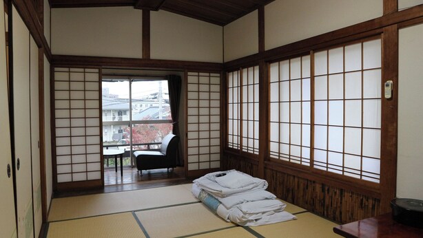 A traditional Japanese room with tatami flooring, a sliding door, and a view of the outside. - Maizurukan (Kirishima)