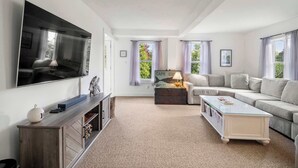 A modern living room with a flat-screen TV, a sofa, a coffee table, and a fireplace.