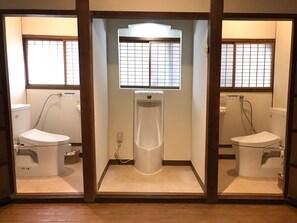 Une salle de bain avec deux toilettes, une douche et une fenêtre à carreaux.