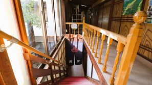 A wooden staircase with a red carpet, a clock, and a sign with Japanese characters.