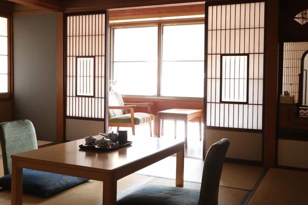 A traditional Japanese room with tatami flooring, a low table with tea set, and sliding shoji doors.