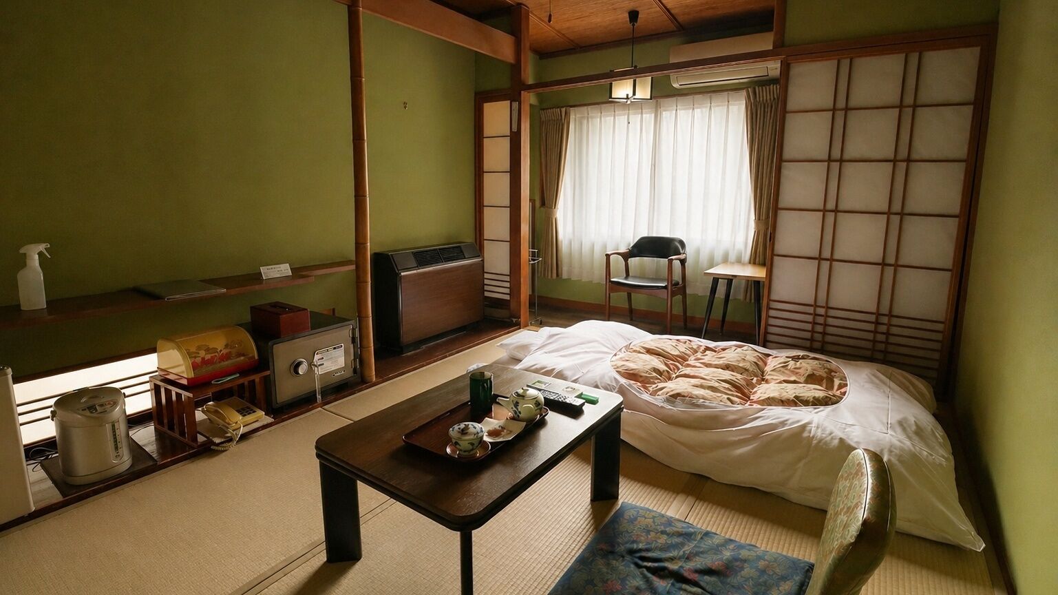 Ein traditioneller japanischer Raum mit Tatami-Boden, einer Futon-Liegefläche, einem kleinen Tisch mit Tee-Zubehör und einem verschiebbaren Shoji-Bildschirm.