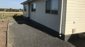 A single-story house with a gravel driveway and a wooden fence. - Cottage Down the Lane Rural Setting (Meredith)